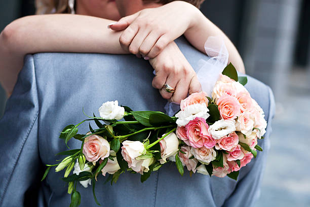 Bride holding bridal bouquet and groom hugging